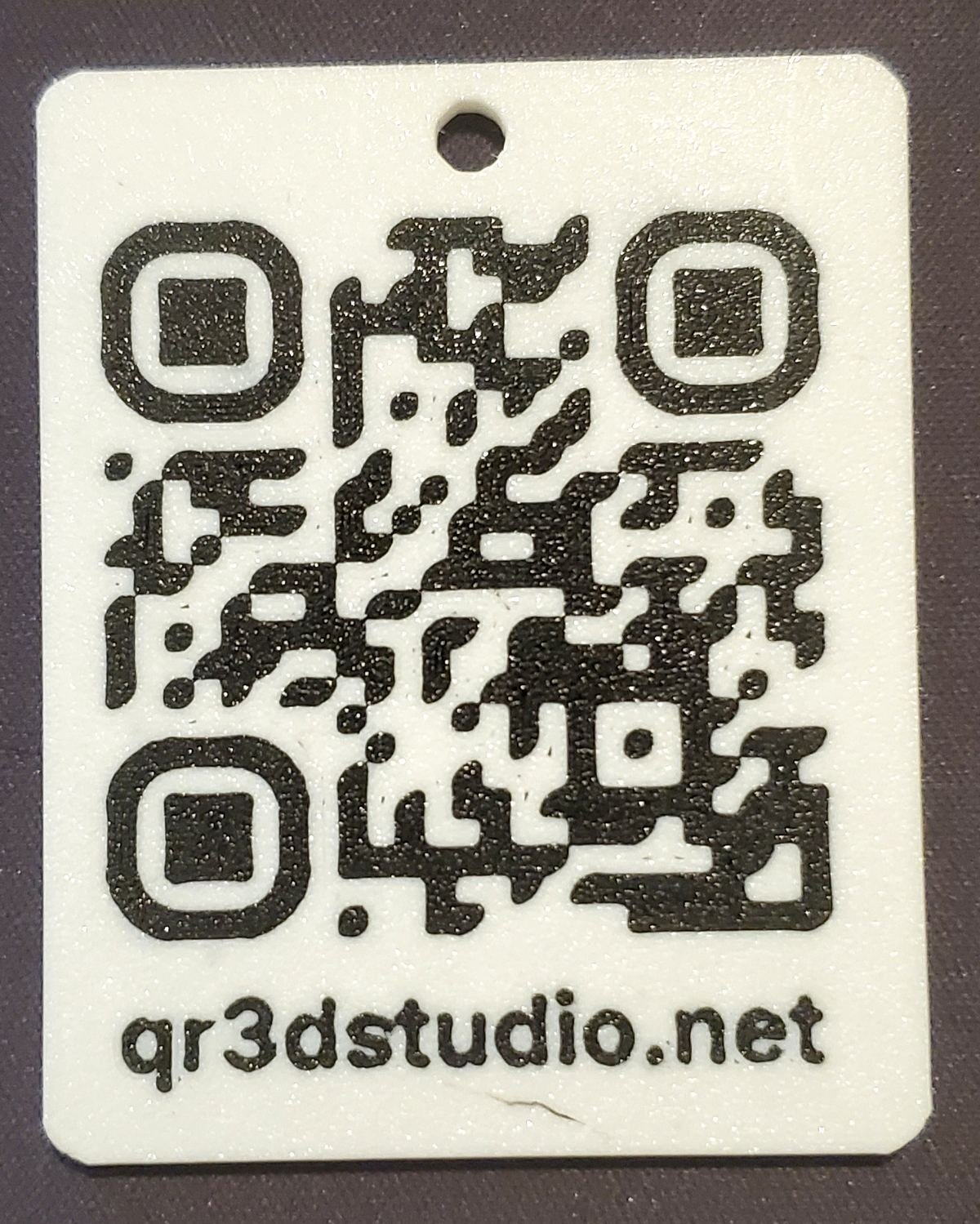 Pieza QR impresa en 3D en PLA blanco con el código en relieve negro, el mismo formato que se usa para la chapa de mascota.
