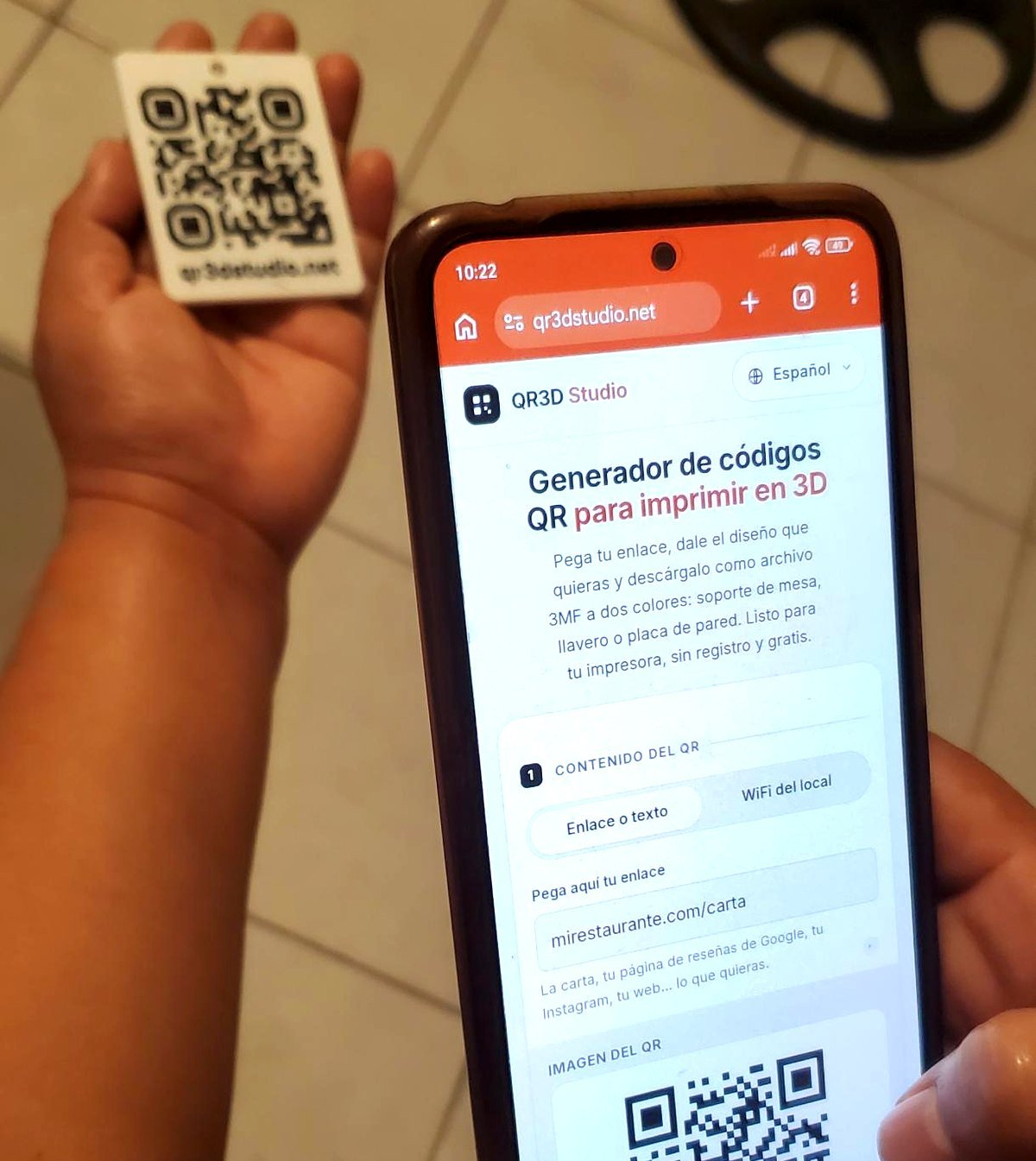 Celular mostrando qr3dstudio.net abierto después de escanear el llavero QR impreso en 3D que se sostiene en la otra mano.